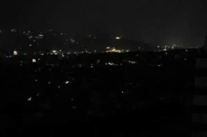 Ночной город Грузии во время блэкаута с редкими огнями на холмах