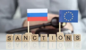 Кубики SANCTIONS между флагами России и ЕС на фоне молотка