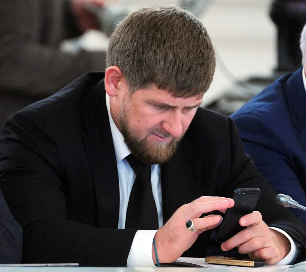 Рамзан Кадиров у чорному костюмі переглядає смартфон за столом