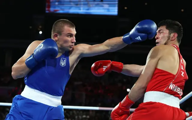 Олександр Хижняк у синій формі завдає удару супернику на рингу