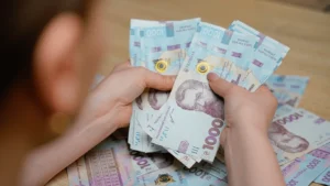 Руки тримають пачки банкнот по 1000 гривень на витрати родини в Києві