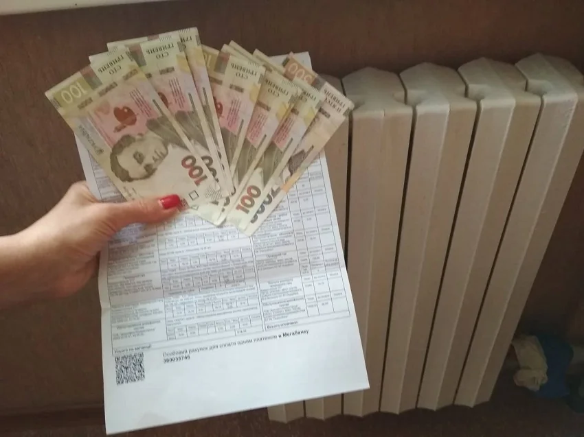 Гривні над рахунком за опалення біля батареї на підготовку до зими