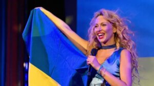 Оля Полякова с украинским флагом и микрофоном на сцене