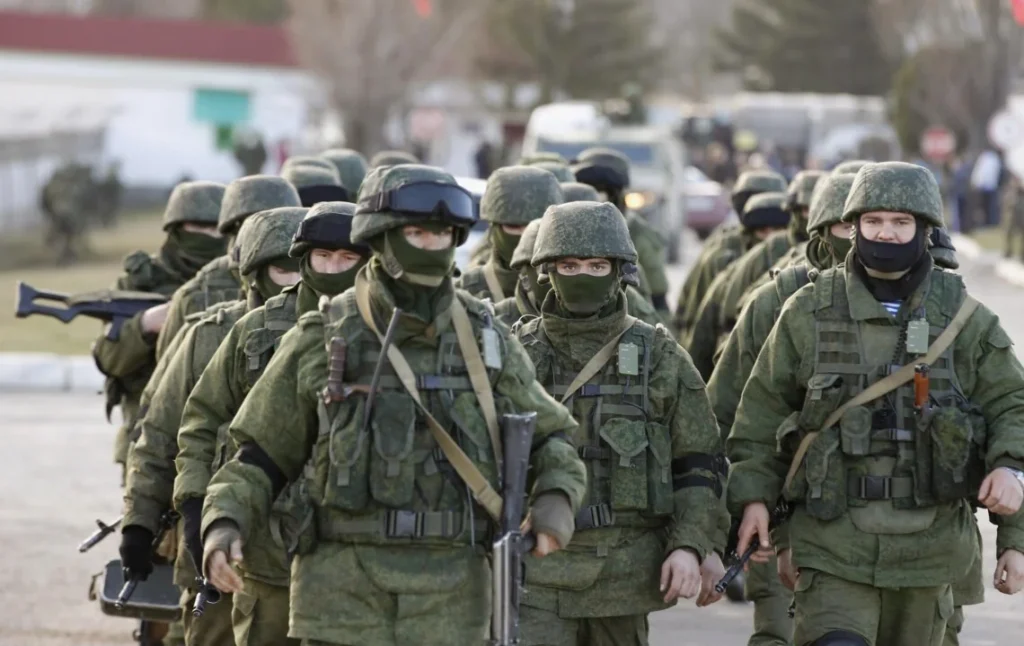 Російські солдати в зеленому камуфляжі з автоматами йдуть строєм