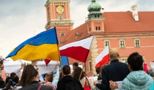 Польська підтримка України: натовп з прапорами України та Польщі на тлі Варшавського королівського замку після російського удару по Києву.
