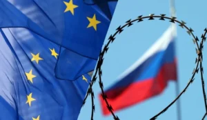 Прапори ЄС з жовтими зірками та прапор Росії за колючим дротом